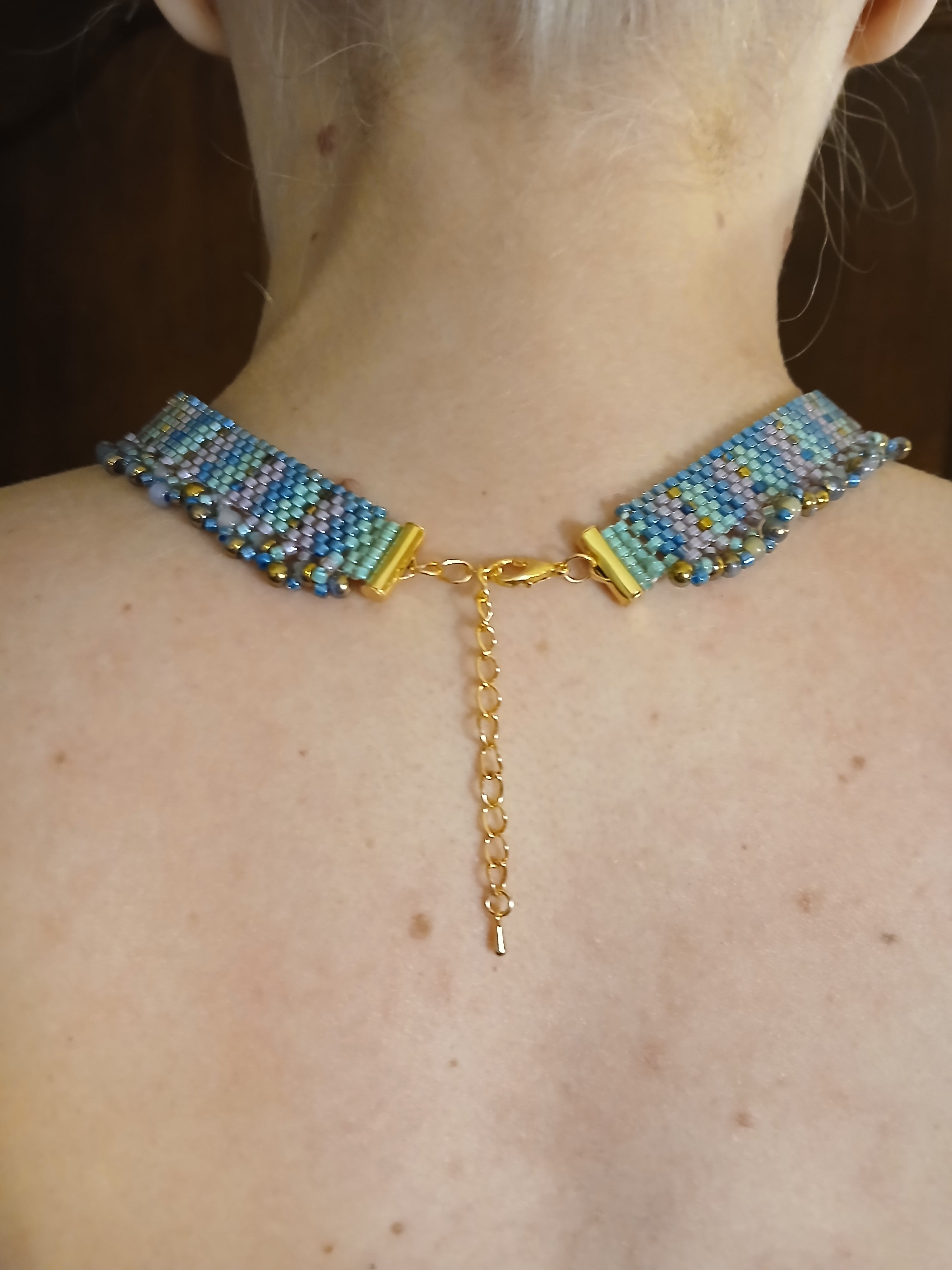 Handwoven choker in seafoam teal and purple from the Mermaid Finery Collection by Regina Creates, featuring a 3.5-inch bead pendant.  Back view (closure) on Model 